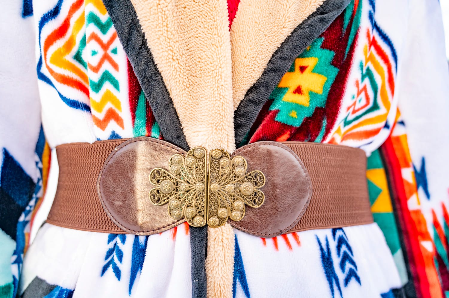 close up of a gold and brown belt buckle against a western themed jacket