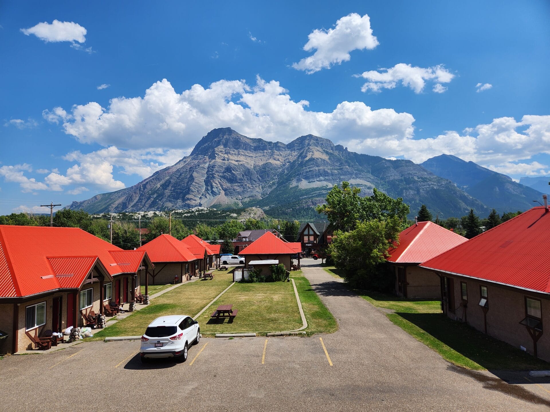 aspen village cabins with red roofs sits in front of the rocky mountains in waterton lake