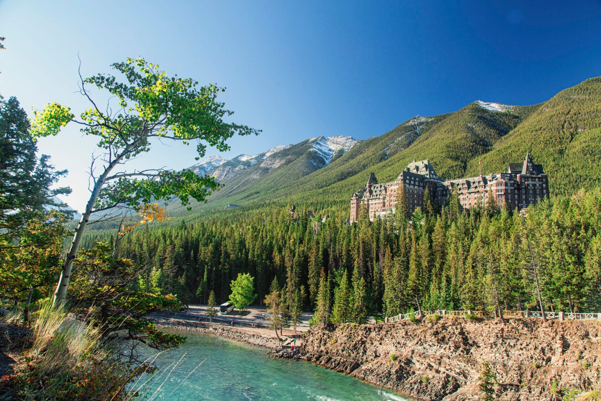 view of fairmont banff springs hotel from a distance, a river and trails are in the forefront