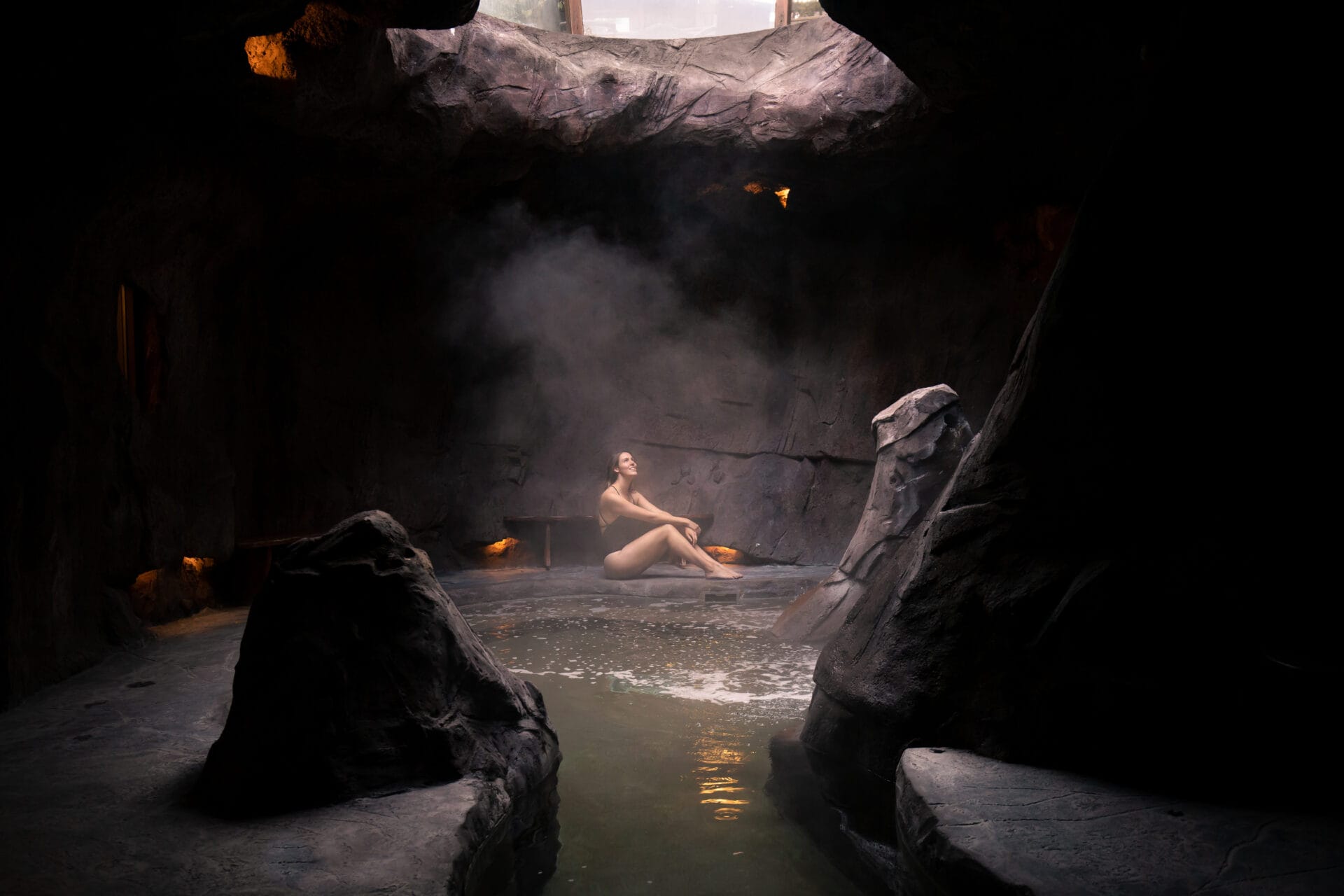 a woman sits next to the cave hot tub at fox inn & suites in banff