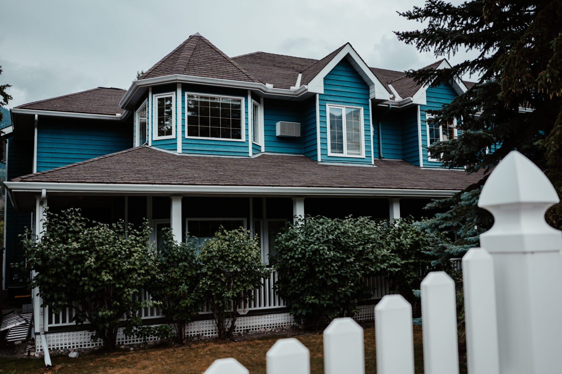 the outside of a blue house with white fence, which is lady macdonald inn