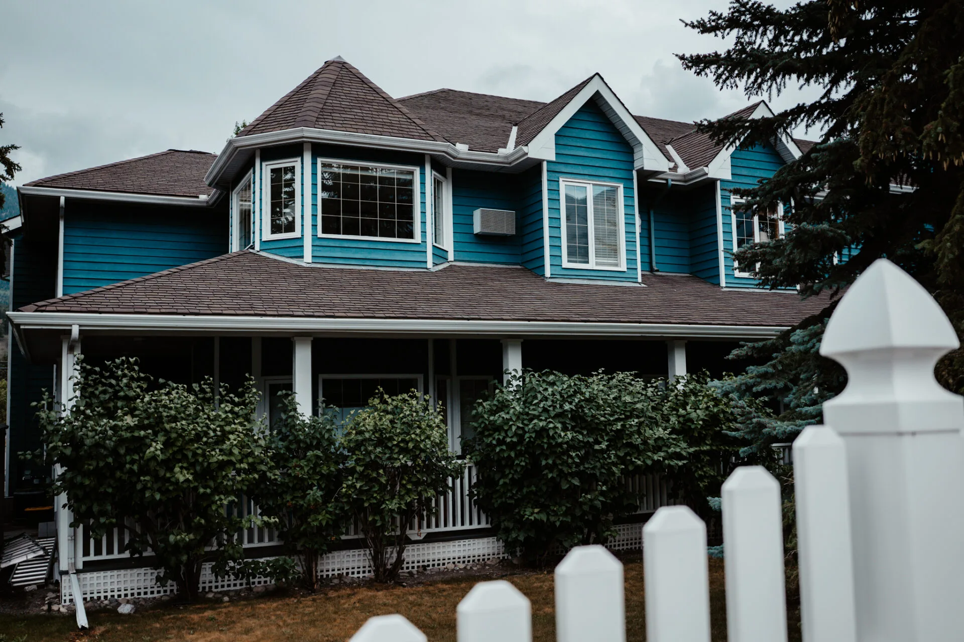 the outside of a blue house with white fence, which is lady macdonald inn