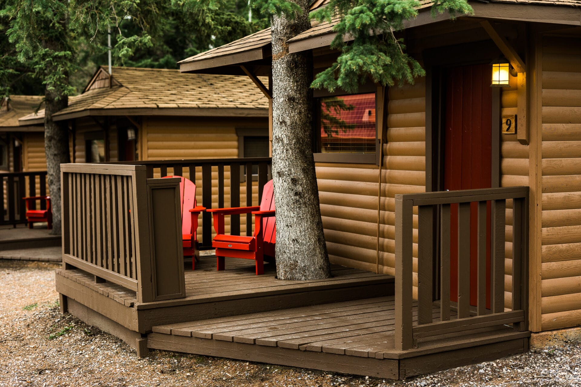 two red chairs sit on the porch of a log cabin at miette mountain cabins in jasper