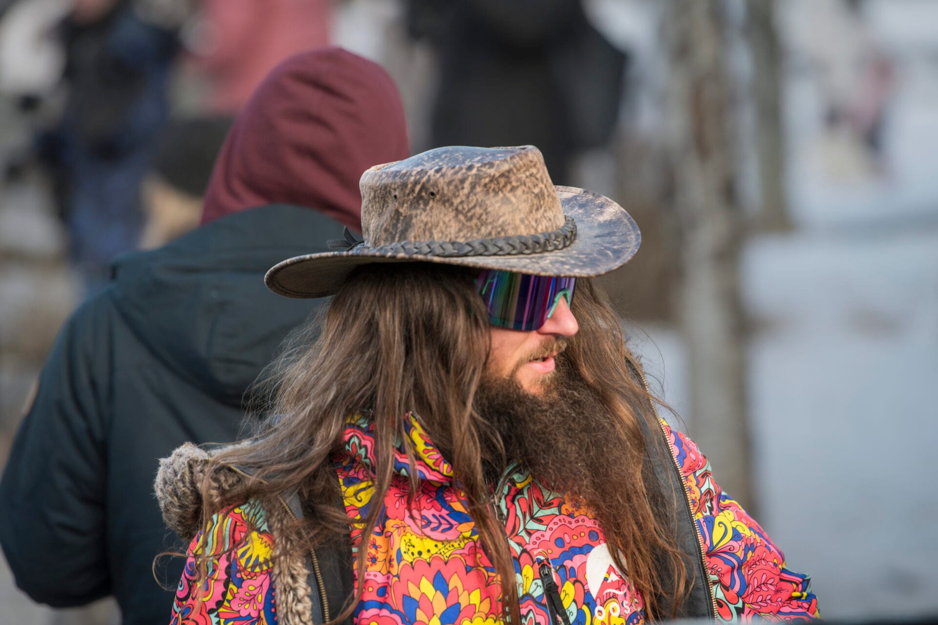 a man wears a rustic cowboy hat with a brightly coloured floral winter coat