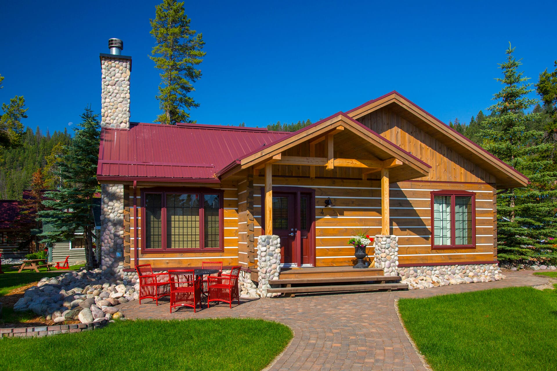 a wood cabin with a red dining set out front at bear hill lodge