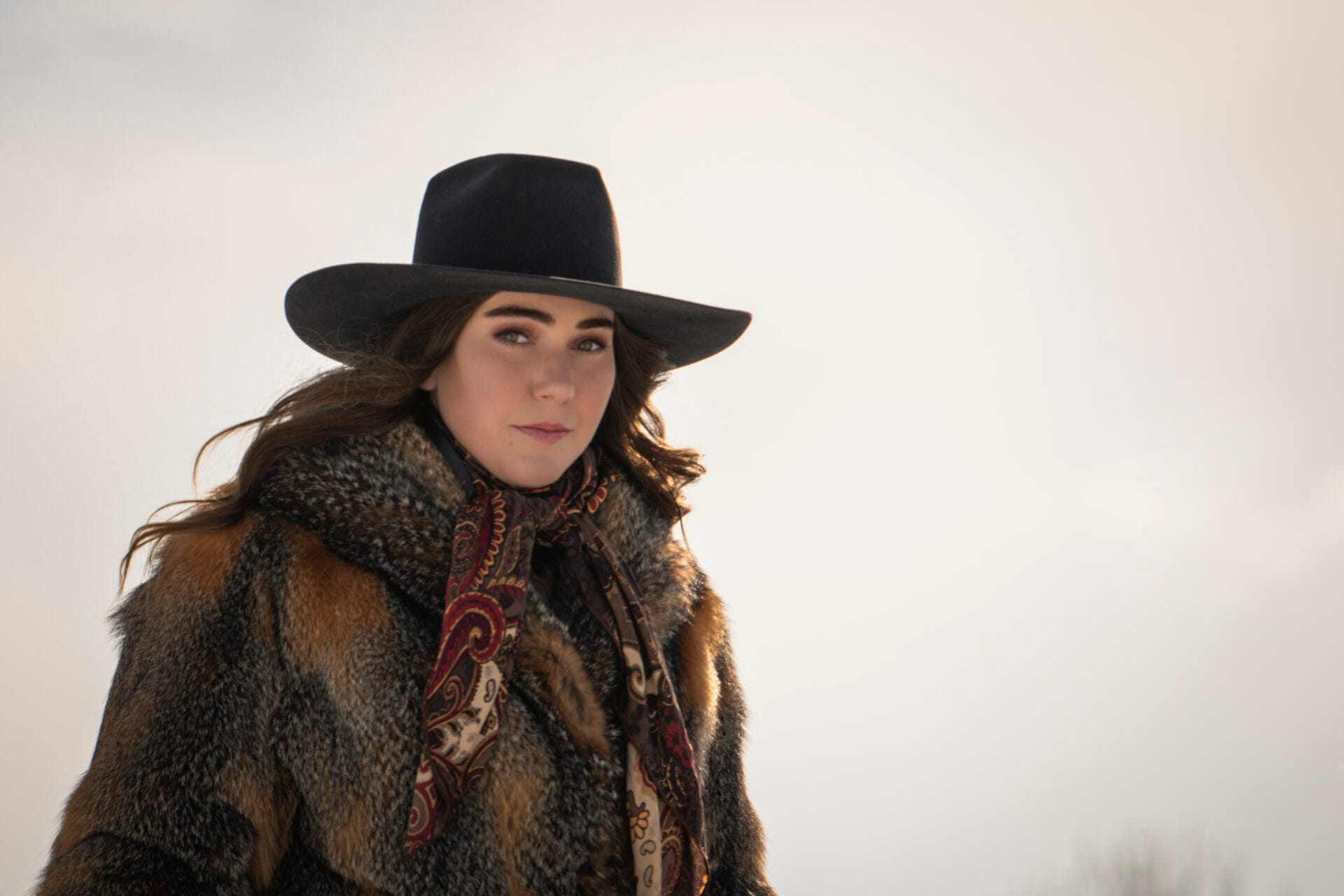 a woman wears a black cowgirl hat and traditional cowgirl clothing