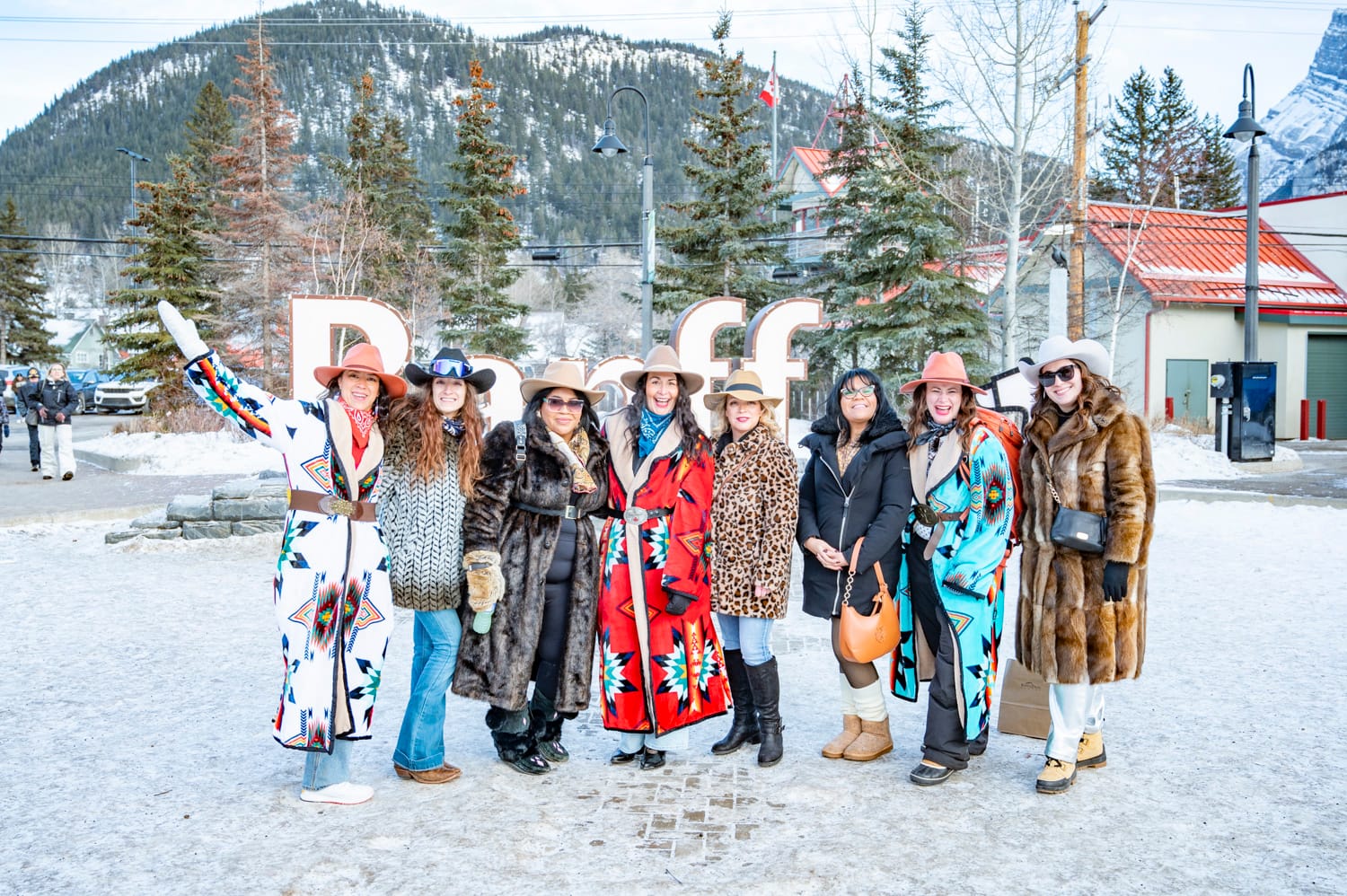 a group of woman wearing their skijoring fashion stand in front of the banff sign