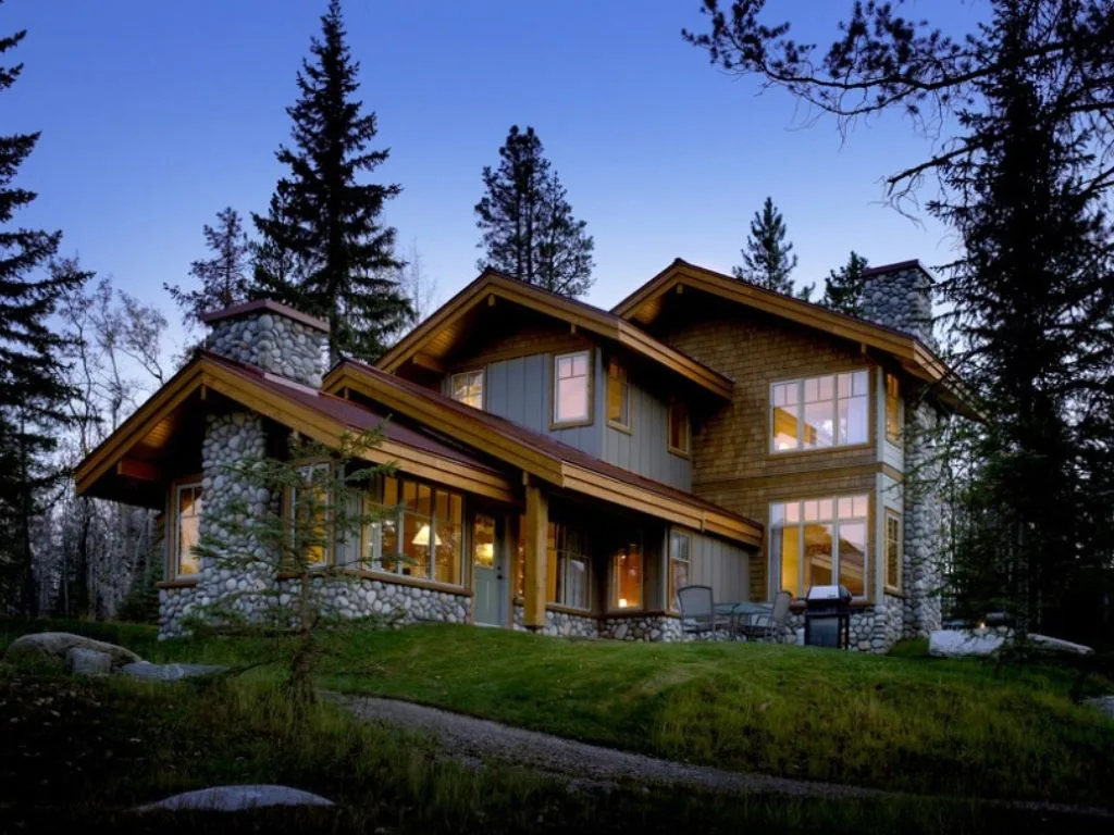 a wood cabin with round stone accents at dusk at the patricia lake bungalows, one of the many Family Reunion Venues In Alberta