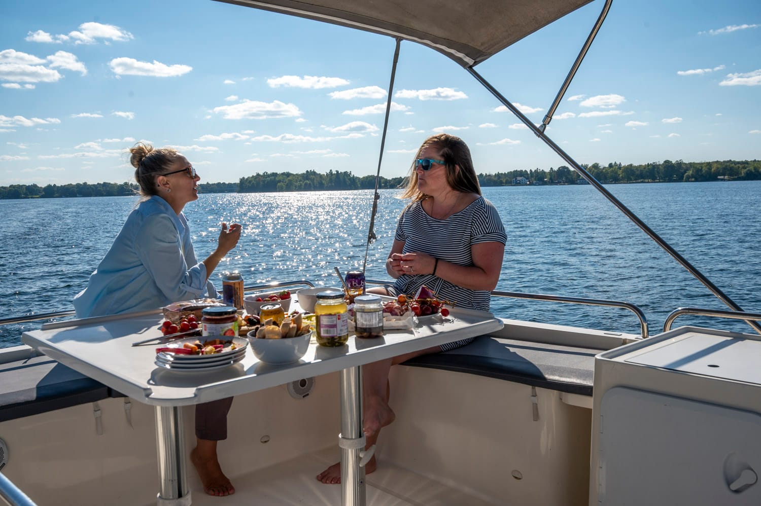 two women enjoying a charcuterie lunch on board the top of a le boat houseboat