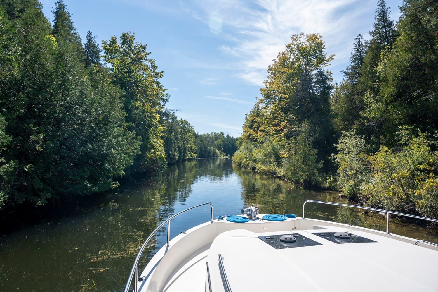 front of the le boat houseboat as it travels down a narrow section of the rideau canal in ontario