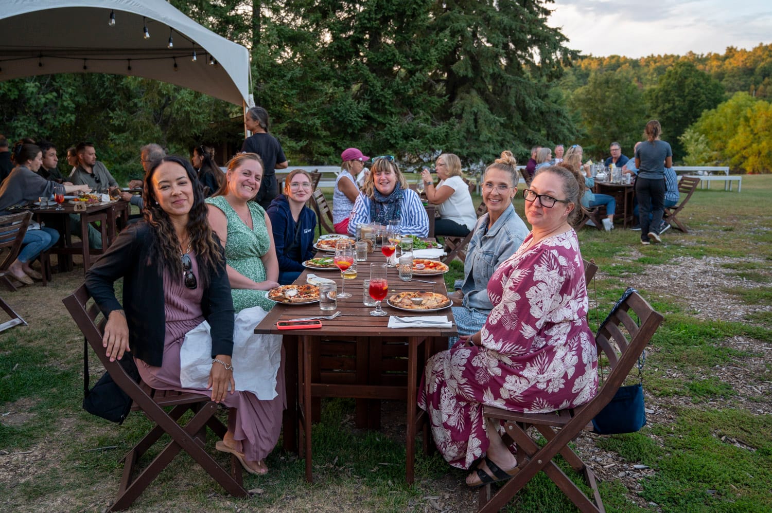 a group of women sitting at a table and smiling at the camera at the Scheuermann Vineyard