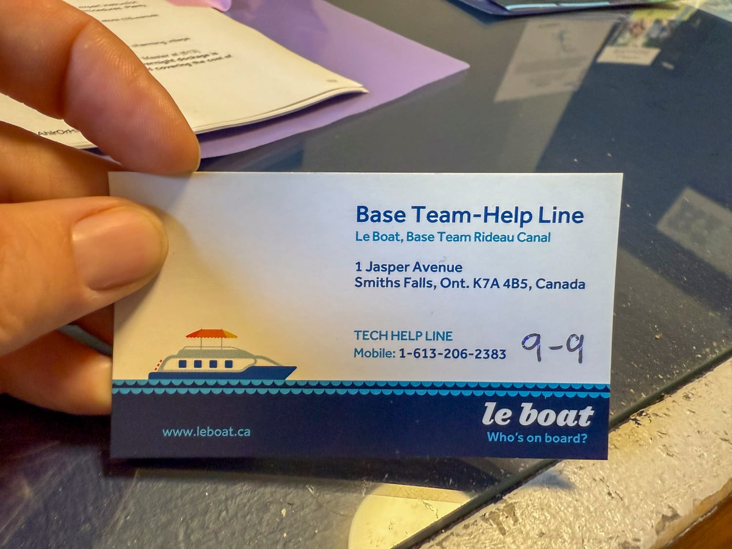 a hand holds a business card that displays the tech helpline phone number for le boat in smith falls