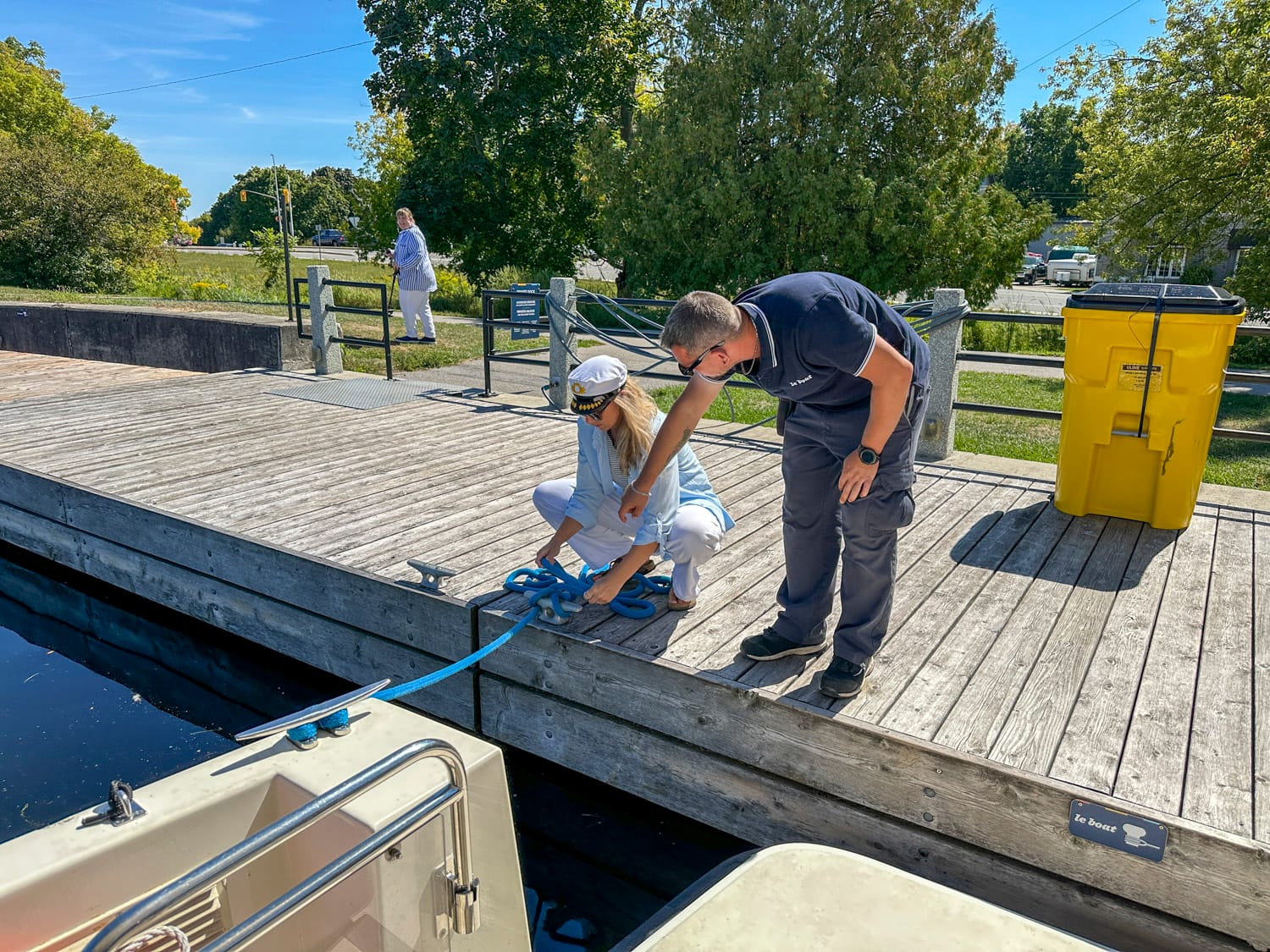 a crew member gets rope training from a le boat staff member on the dock