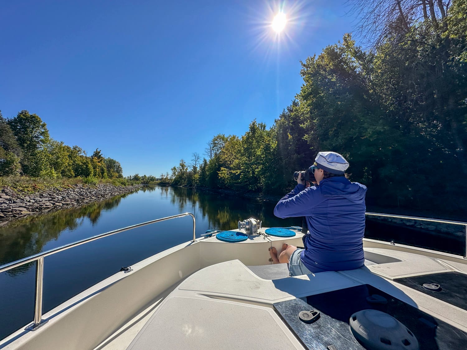 a woman sits at the front of a le boat, holding her camera and taking a photo of the scenery