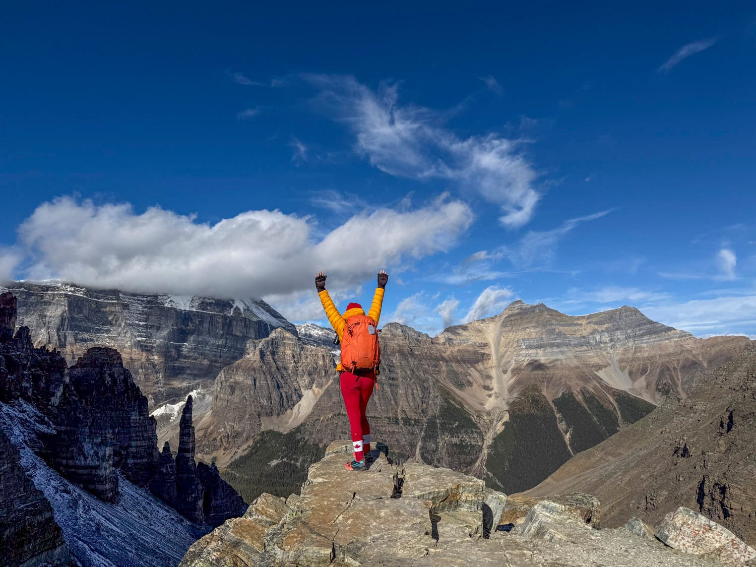 a woman hiker with her hands in the air at the top of the sentinel pass hike in banff