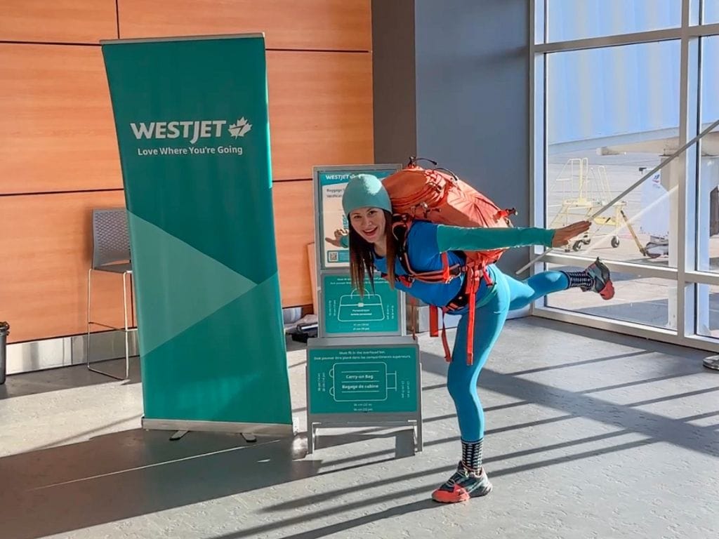 woman pretending to fly like an airplane beside a westjet sign in the abbotsford airport