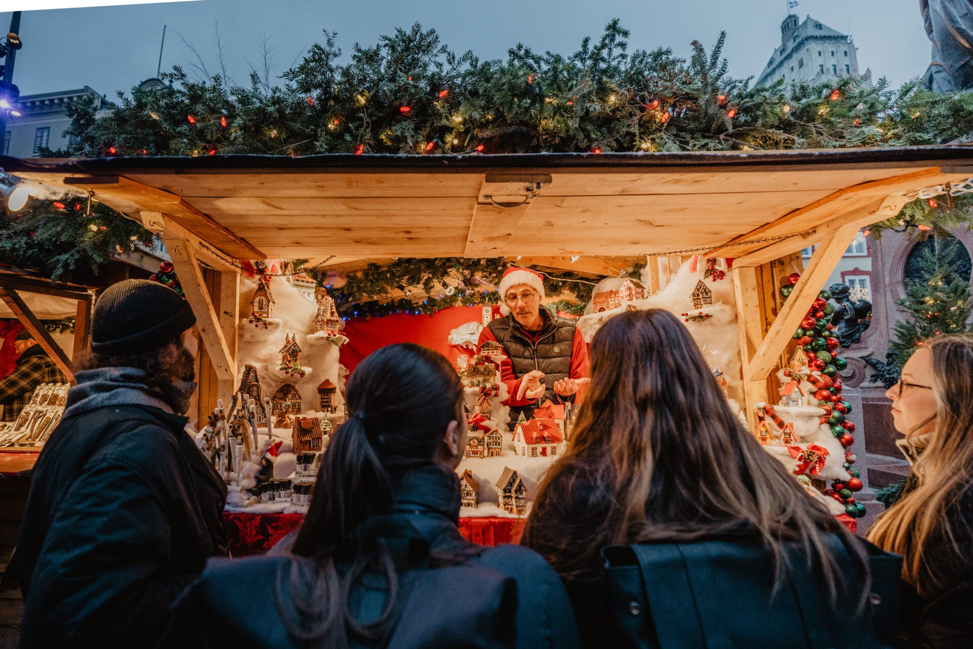 four people standing admiring the crafts for sale at the german christmas market in quebec city