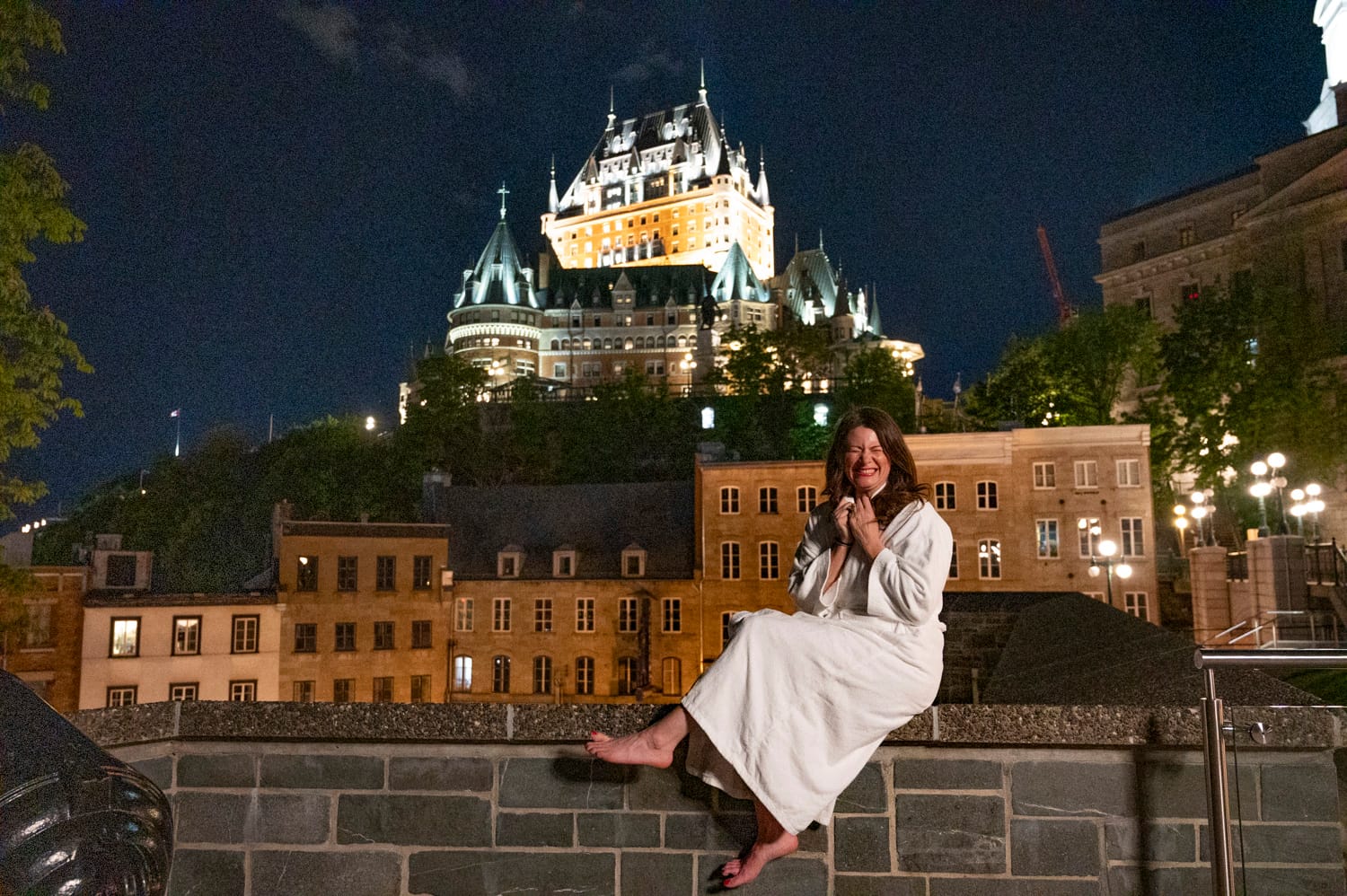 woman sits in front of The Fairmont Le Château Frontenac photo is taken from Montmorency Park National Historic Site