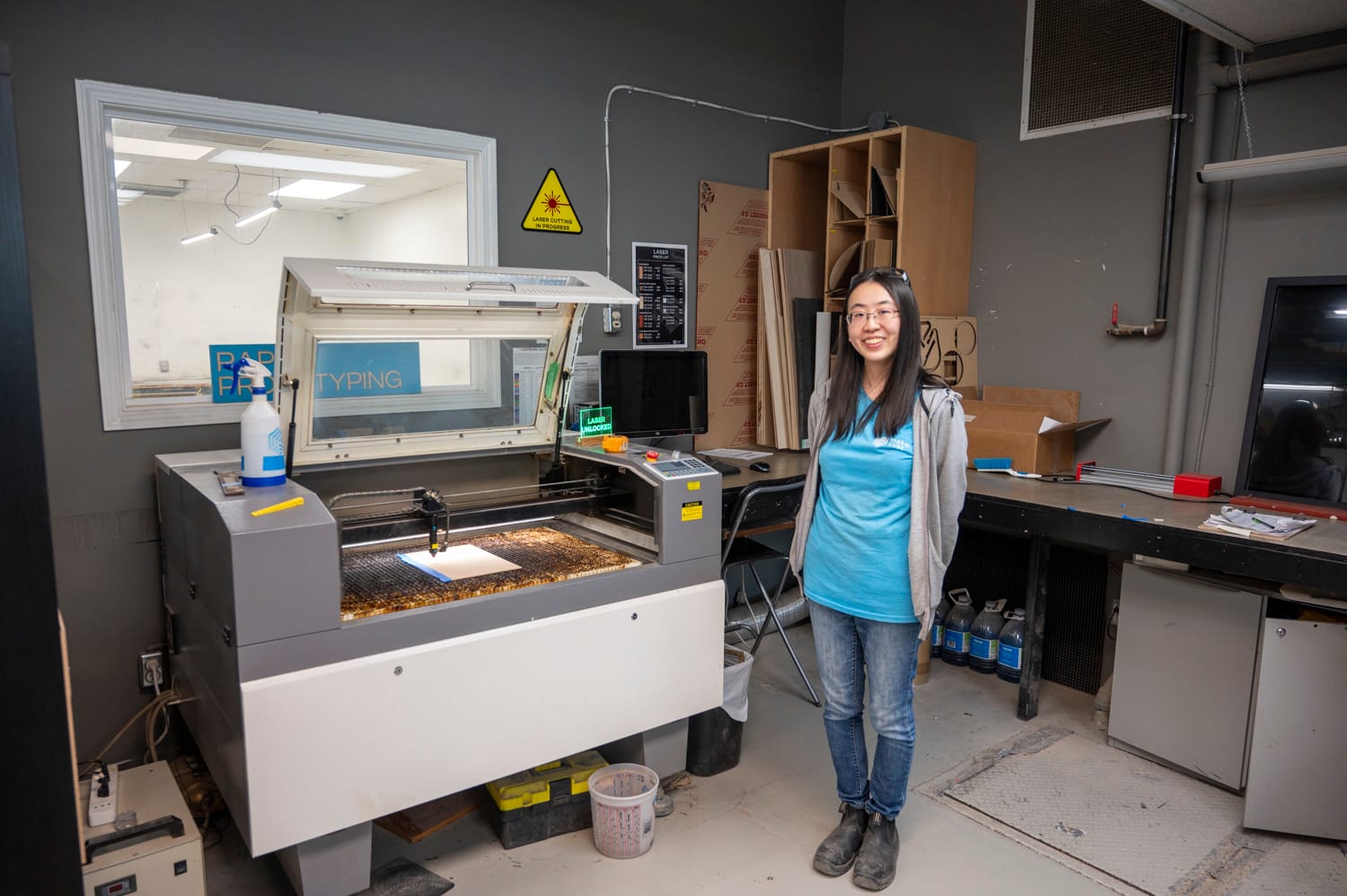 a langley maker cube makerspace employee stands next to the CNC laser engraving machine