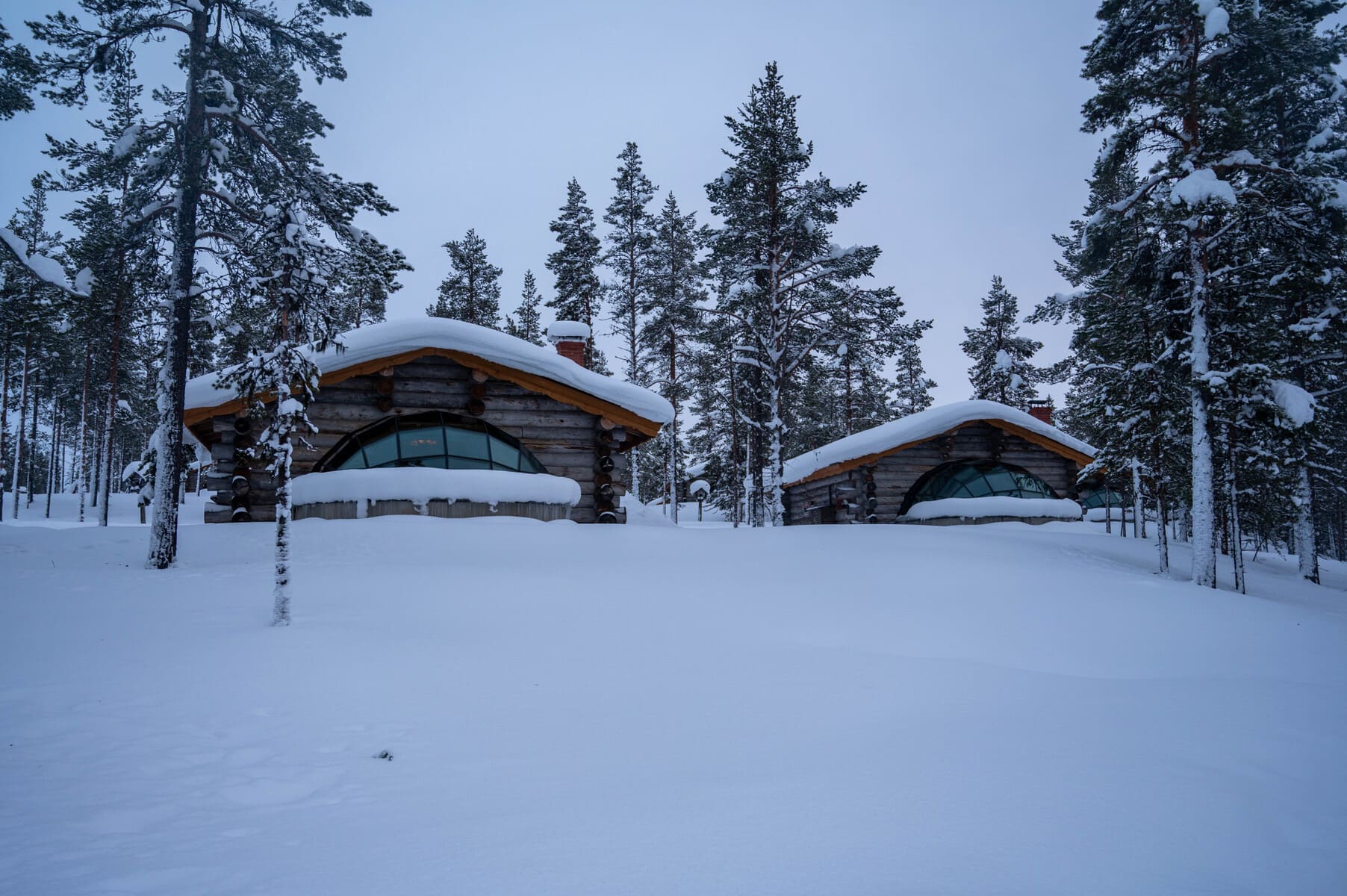 Front view of two kelo glass igloos at Kakslauttanen Arctic Resort, Finland, surrounded and covered in snow