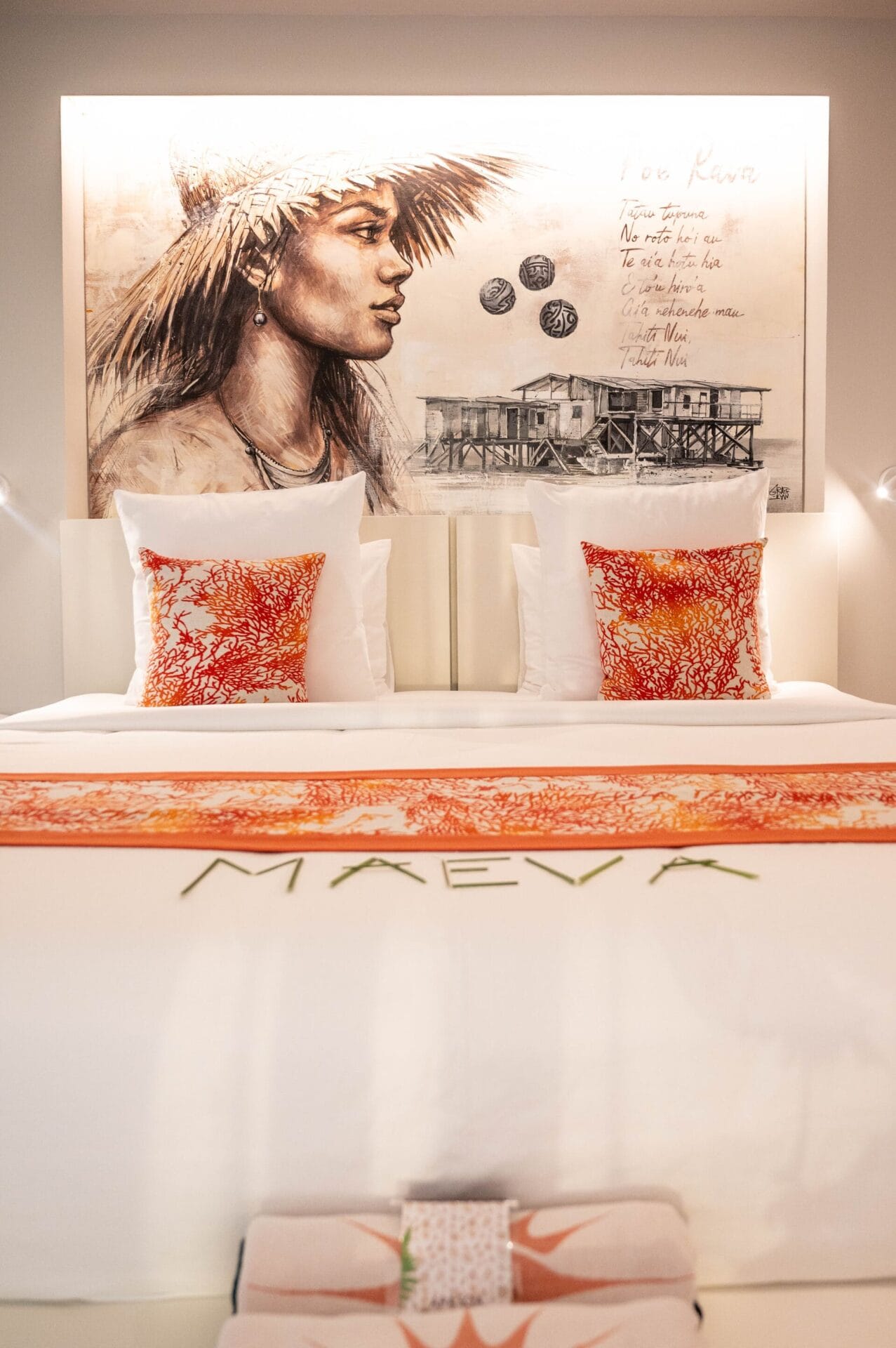 Inside the Apatoa Raiateta Luxury Villas - a king-size bed with beautiful, rich linens, and a custom mural by Tahtian Artist, Jops, to center it all with a spirit of “Maeva”