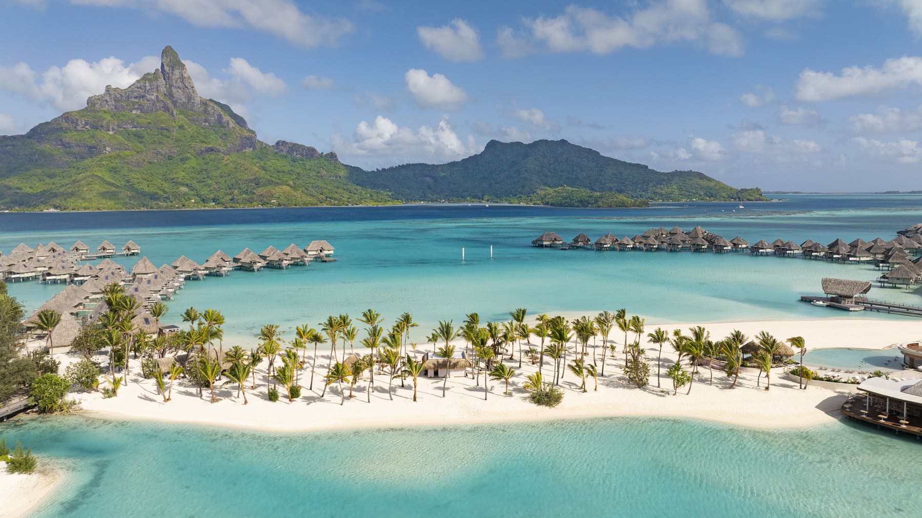 overwater bungalows, white sand beach, palm trees, and green mountains at Westin Bora Bora resort