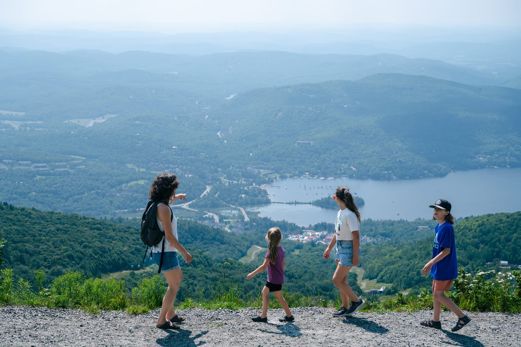 family hiking mountain overlook with lake, boats, and town in background; scenic mountain view, outdoor recreation