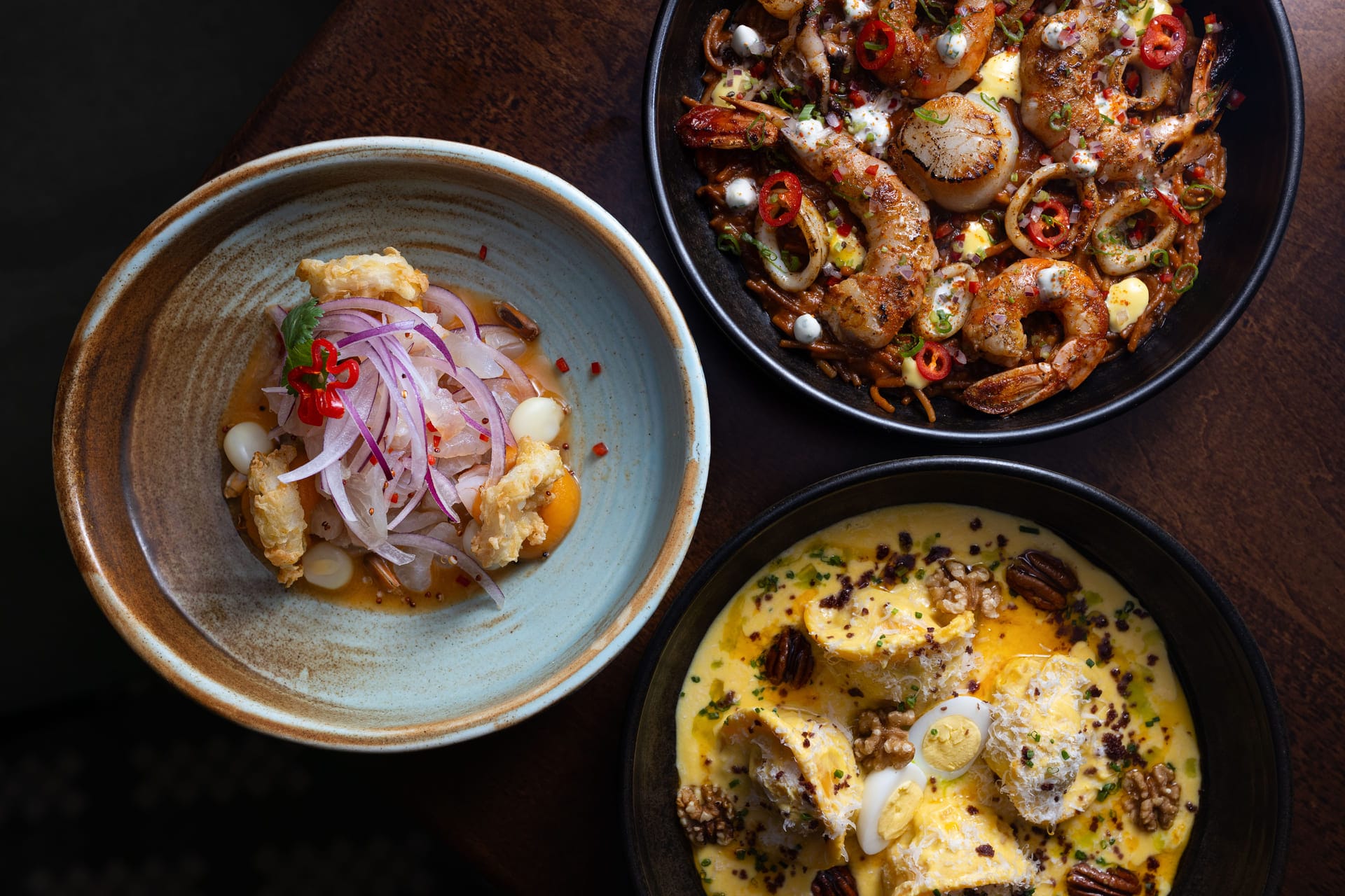 three colorful dishes on a wooden table: