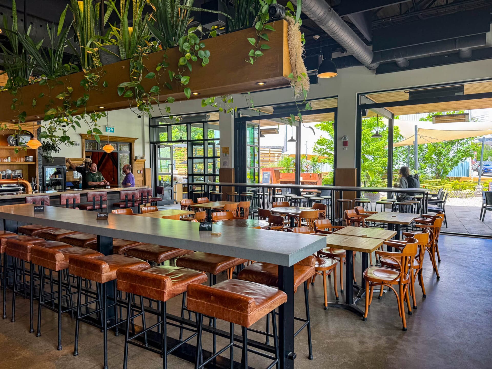 Brasserie Dieu du Ciel in Saint-Jérôme -modern restaurant interior with concrete bar, leather stools, and an outdoor patio with greenery