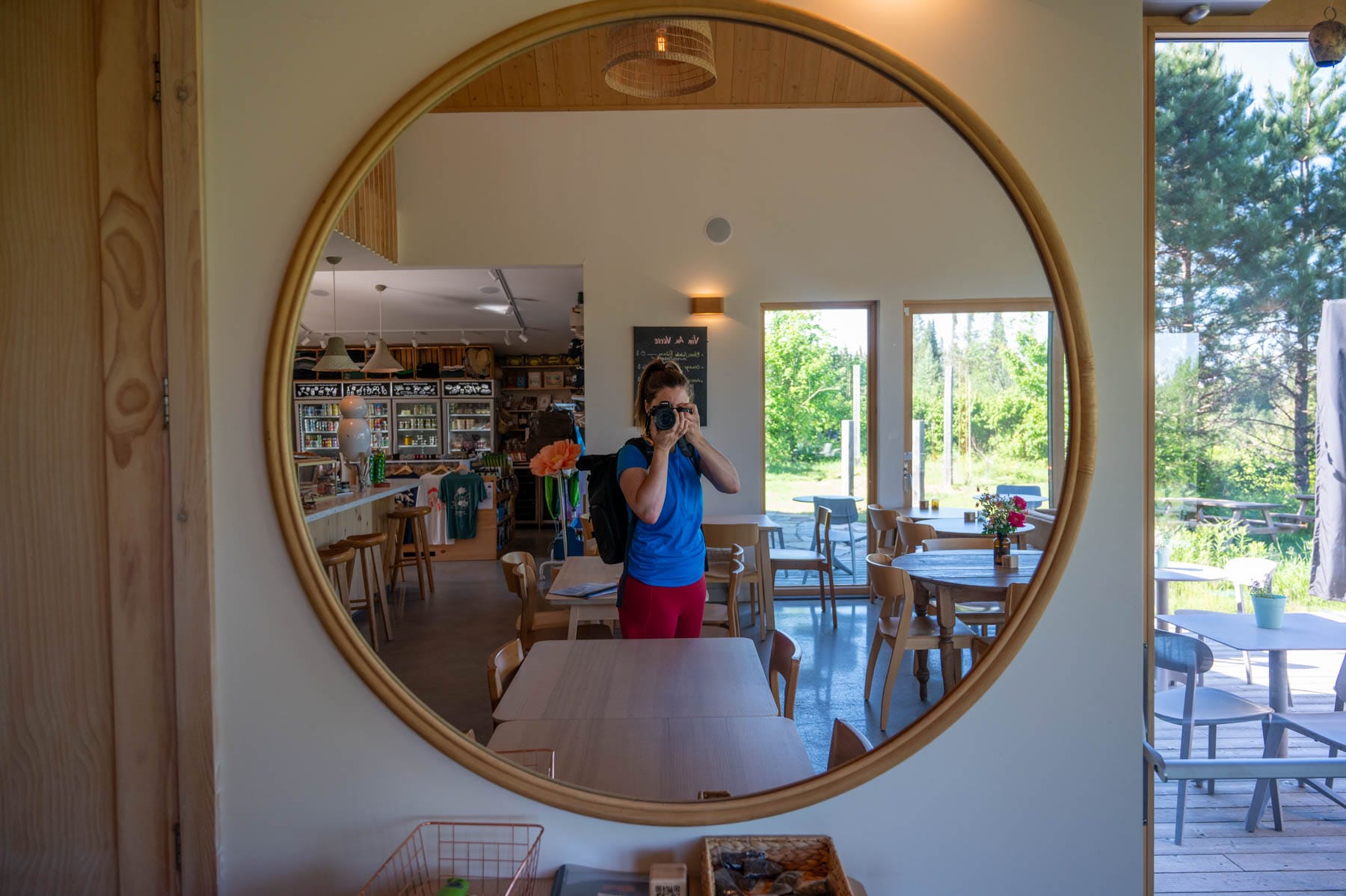 person taking a mirror selfie with a camera, a store and patio in the background