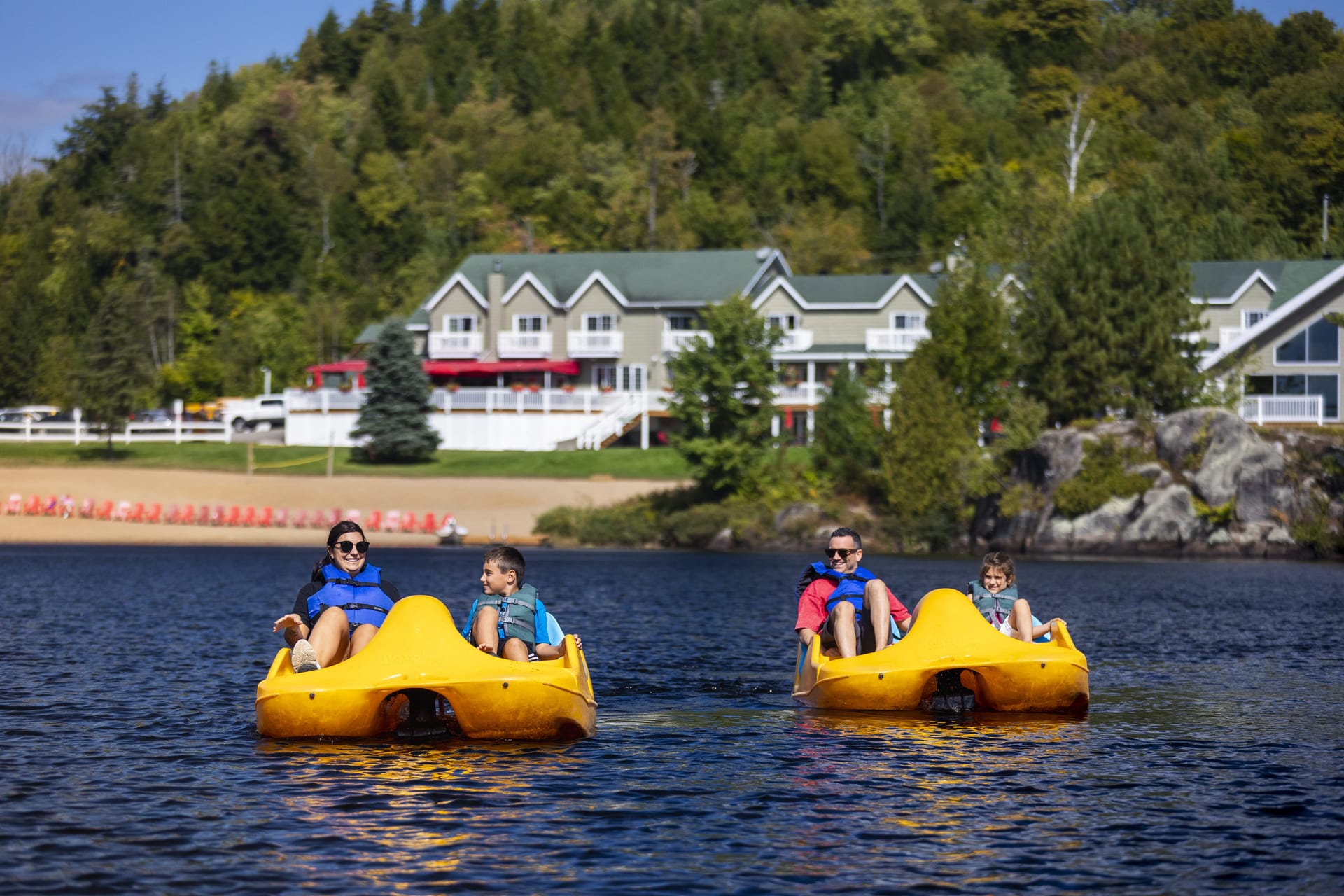 Family pedal boating on lake, resort in background, summer water activity, outdoor recreation, family vacation