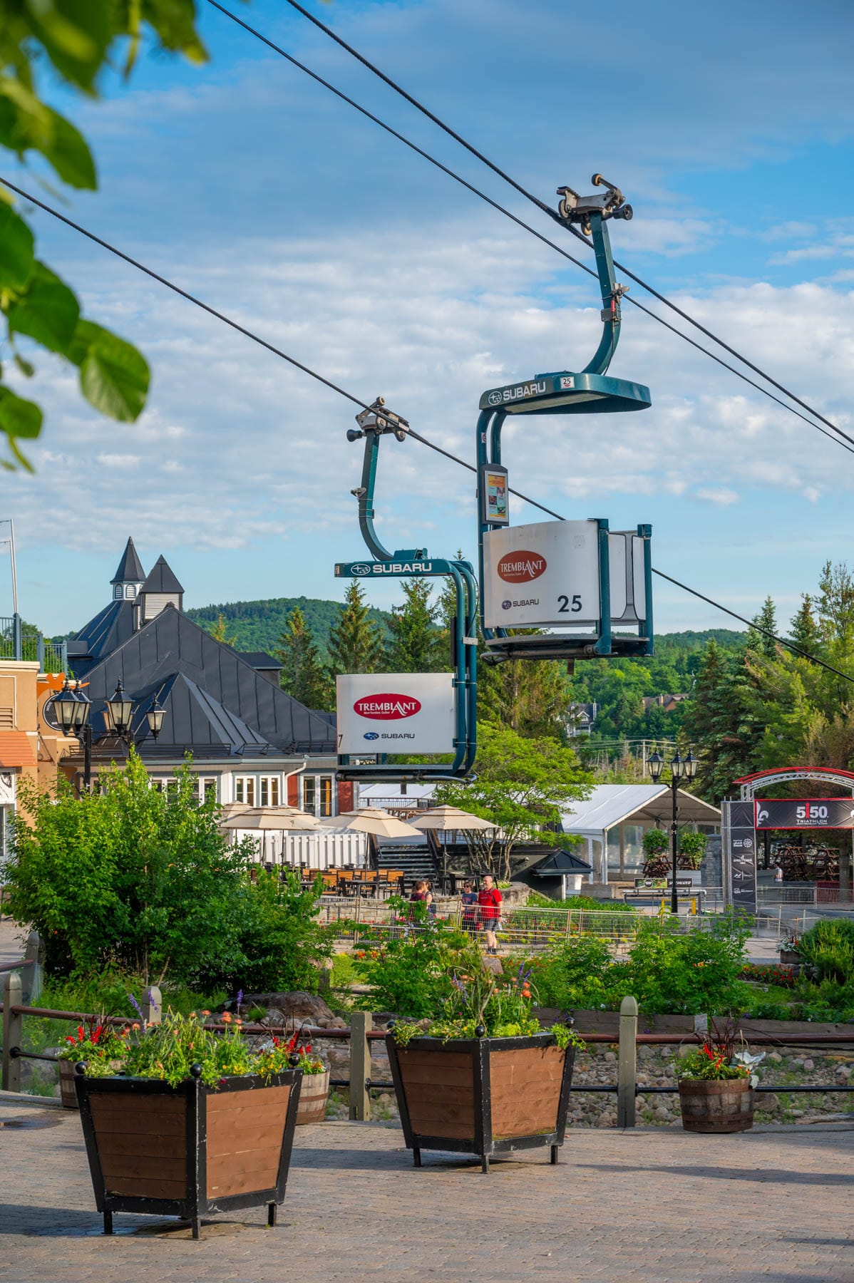 Cabriolet open-air lift over Tremblant village with green trees and flowers