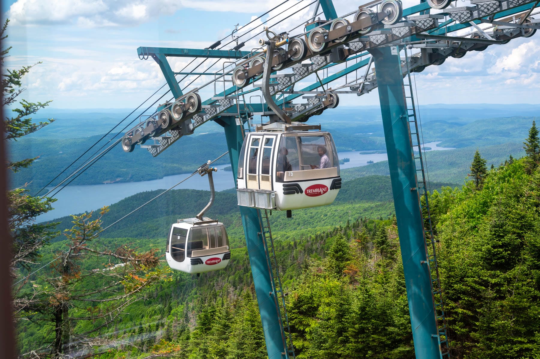 to Panoramic Gondola cabins in Tremblant ascend a mountain, overlooking a lake and forested hills