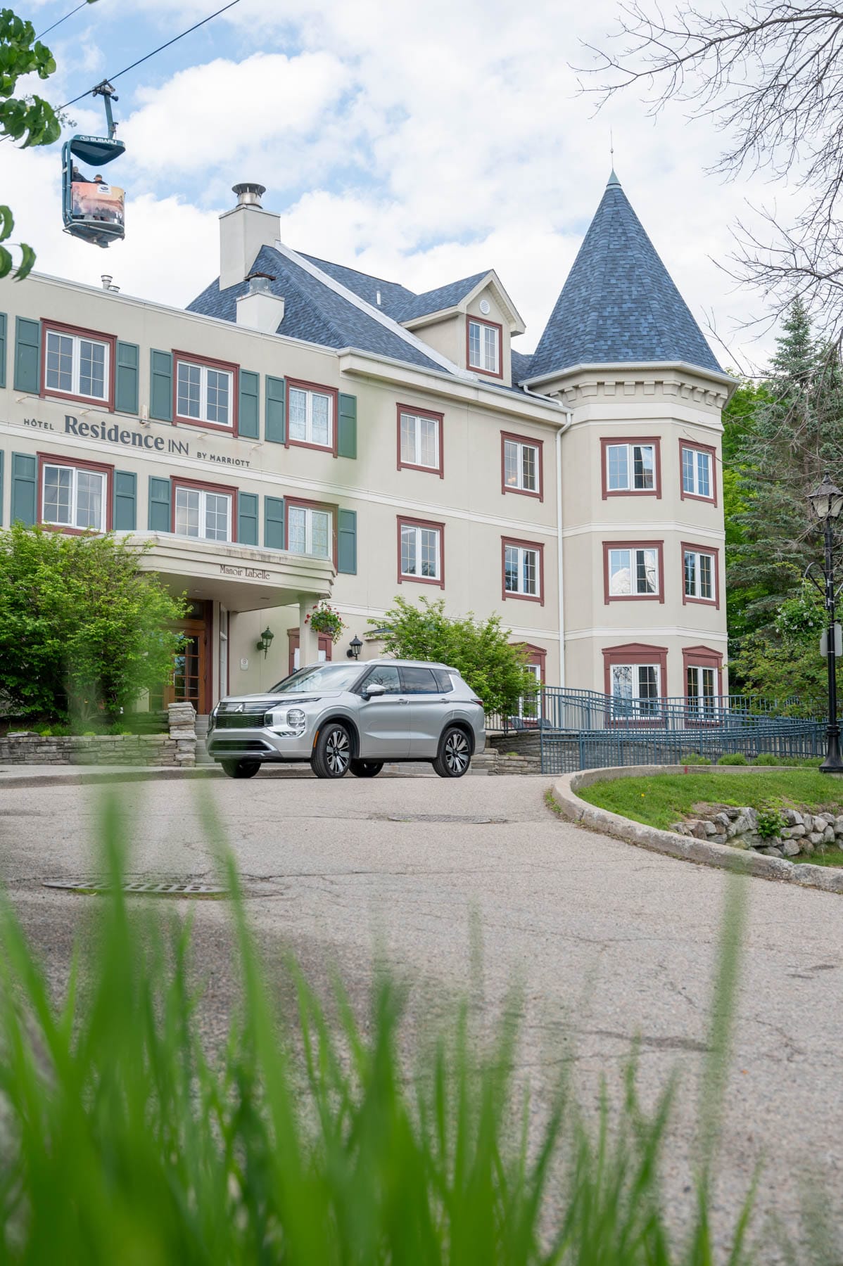 Silver SUV in front of Hotel Residence Inn by Marriott with a blue turret and cable car in the sky