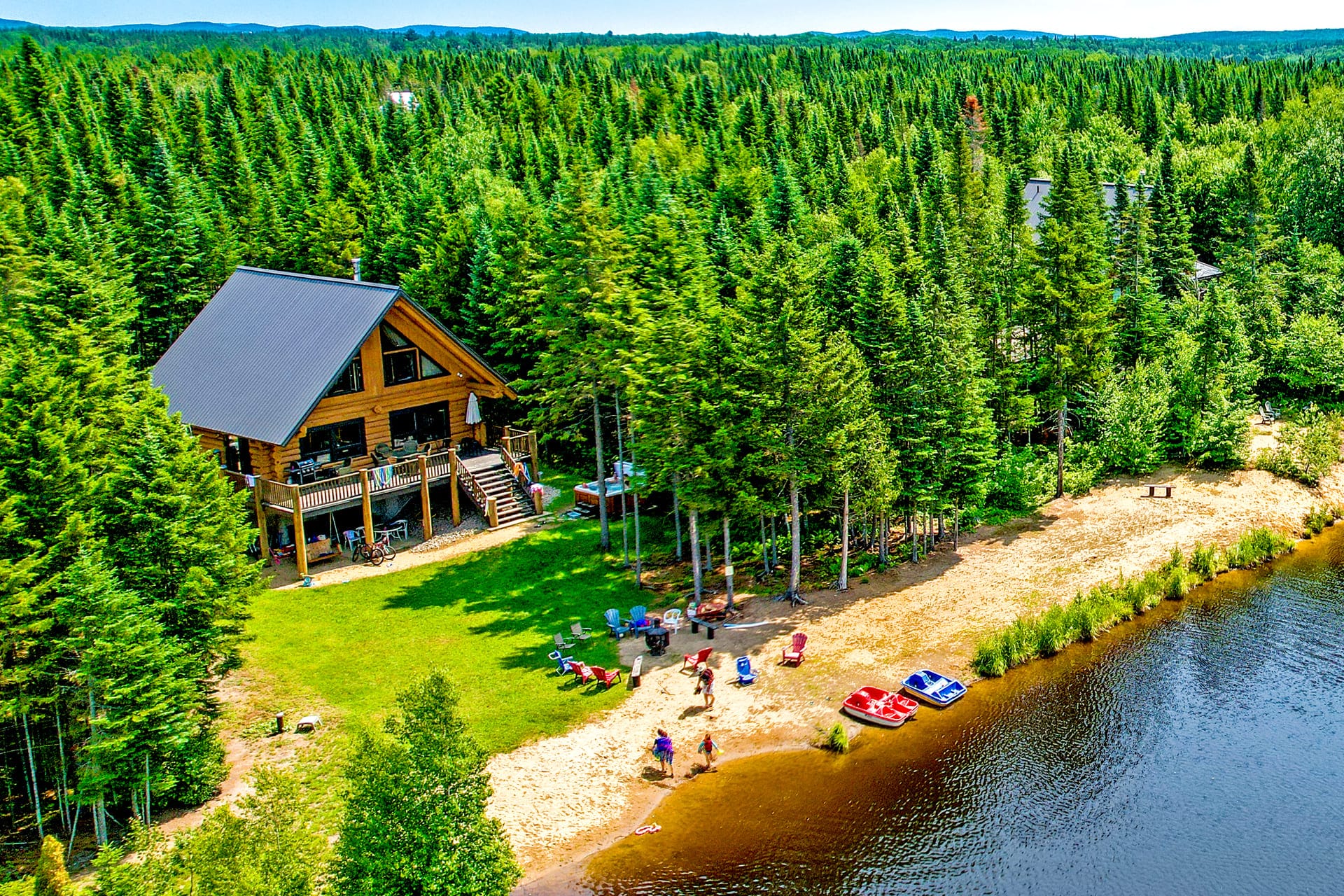 Family reunion in Quebec, at Au Chalet en Bois Rond, in a pine forest, next to a lake with a sandy beach, colorful chairs, and pedal boats