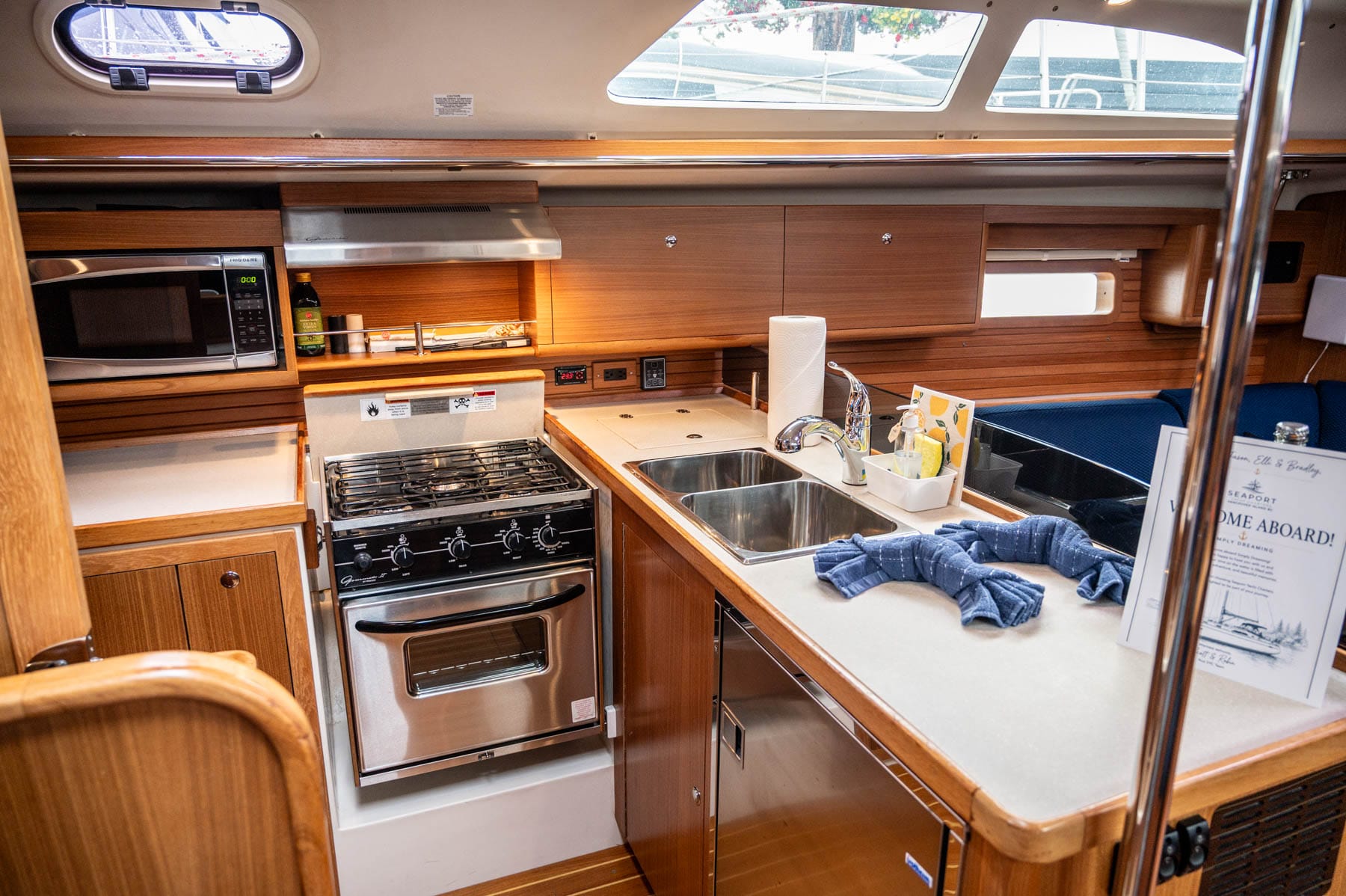 the galley inside Simply Dreaming - half-size refrigerator, cubby freezer, a three-burner propane stove, oven, microwave, sink