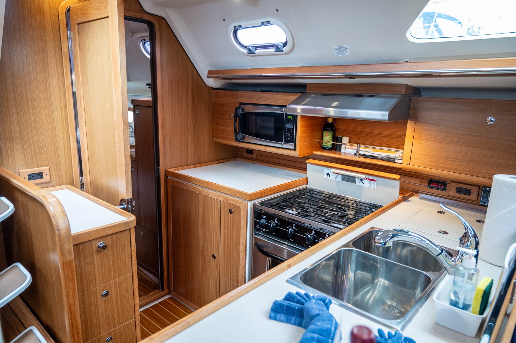 the galley inside Simply Dreaming - half-size refrigerator, cubby freezer, a three-burner propane stove, oven, microwave, sink