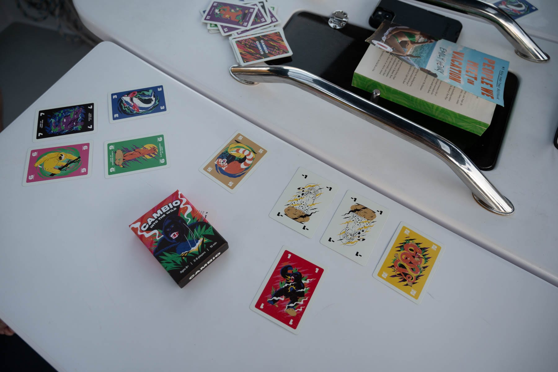 cambio card game spread on a white table with animal-themed cards, the game box, and a book
