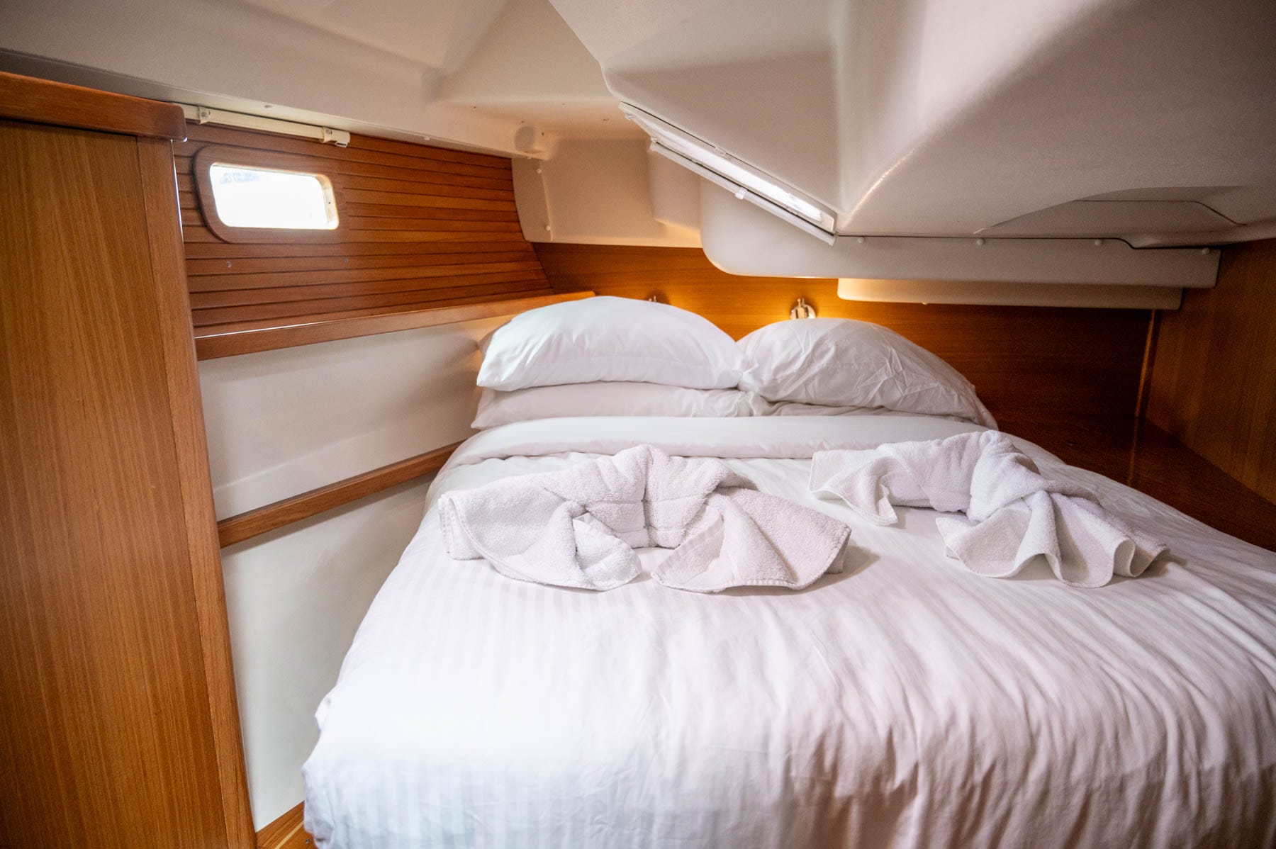 stateroom inside Simply Dreaming - white bed with folded towels, wood paneling