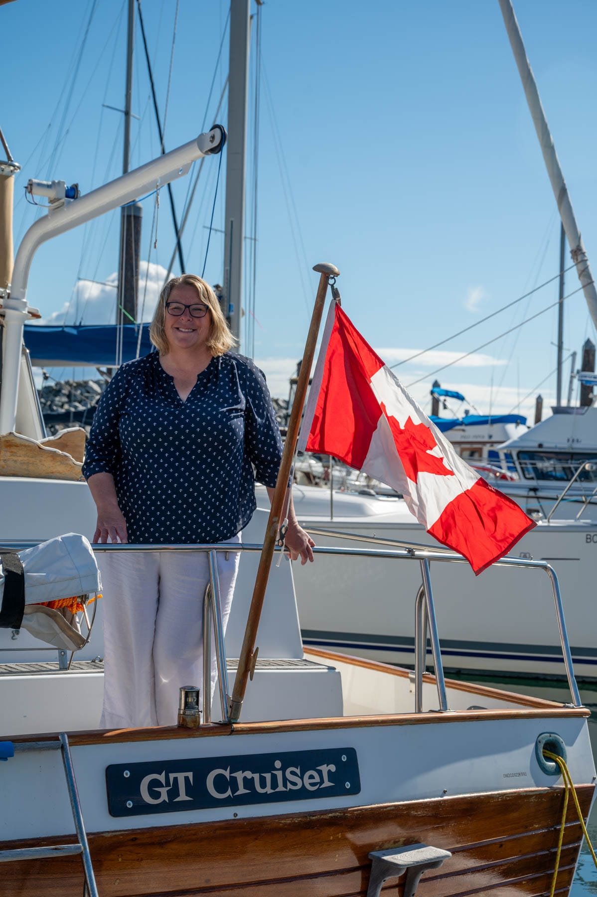 Robin McKeown smiling on a boat with a Canadian flag, other boats in background