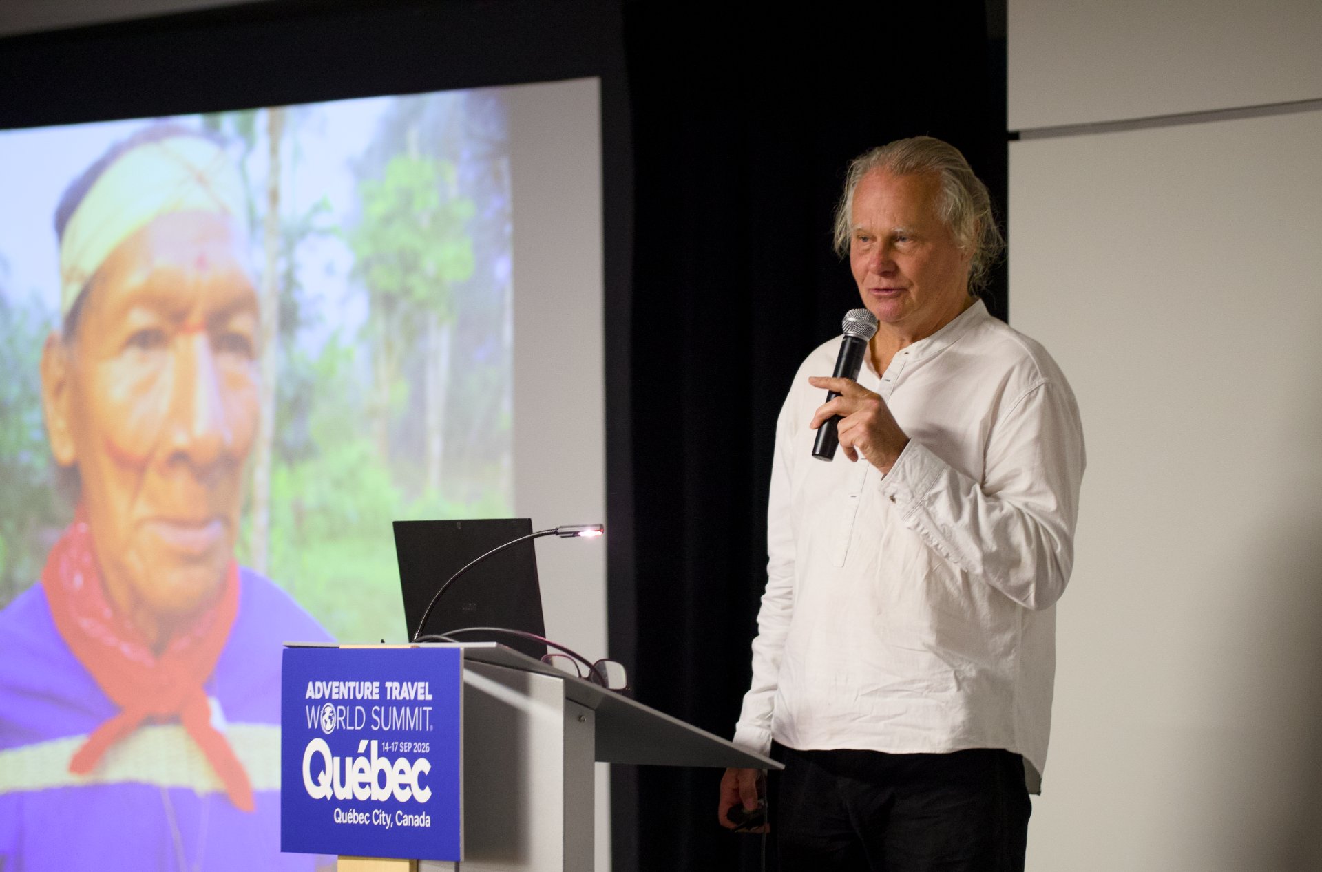 anthropologist, author, and filmmaker Wade Davis speaking at a podium during the Adventure Travel World Summit (ATWS) held in Qu&eacute;bec City, Canada