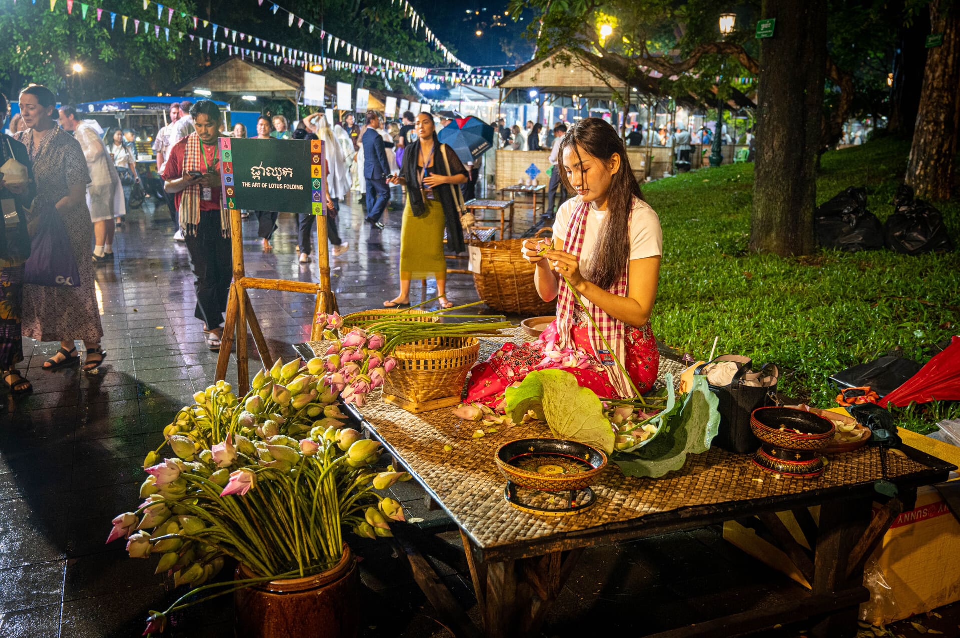 woman folding lotus flowers at a night market cultural stall during the Wat Phnom Fair in Phnom Penh, GX Cambodia