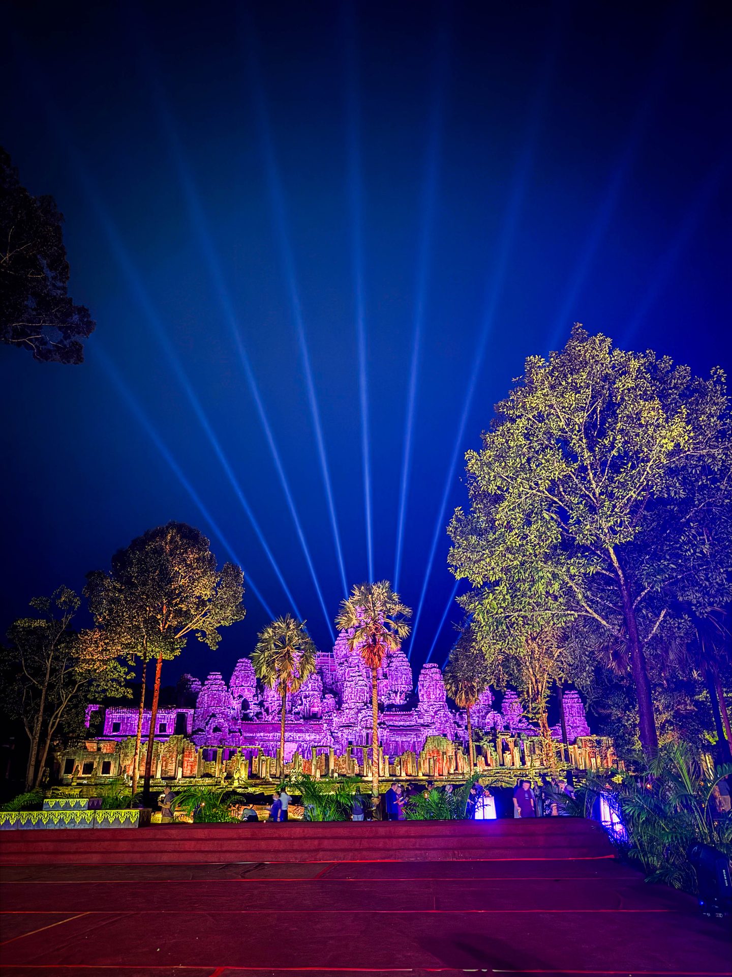 GX Cambodia – Photo Credit Jami Savage, AdventureAwaits.ca (198 of 204) Bayon Temple in Angkor Thom, Siem Reap, Cambodia, illuminated with purple stage and laser lighting at night