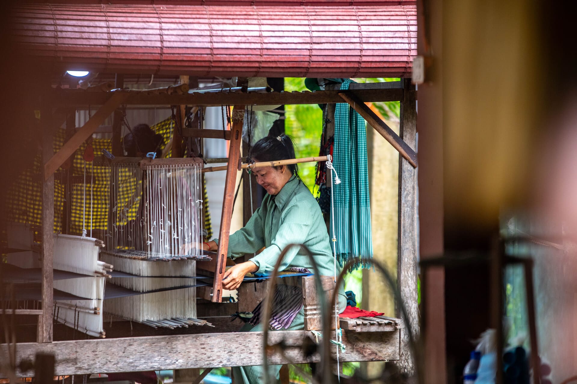 Woman weaving textile by hand on traditional wooden loom handicraft workshop