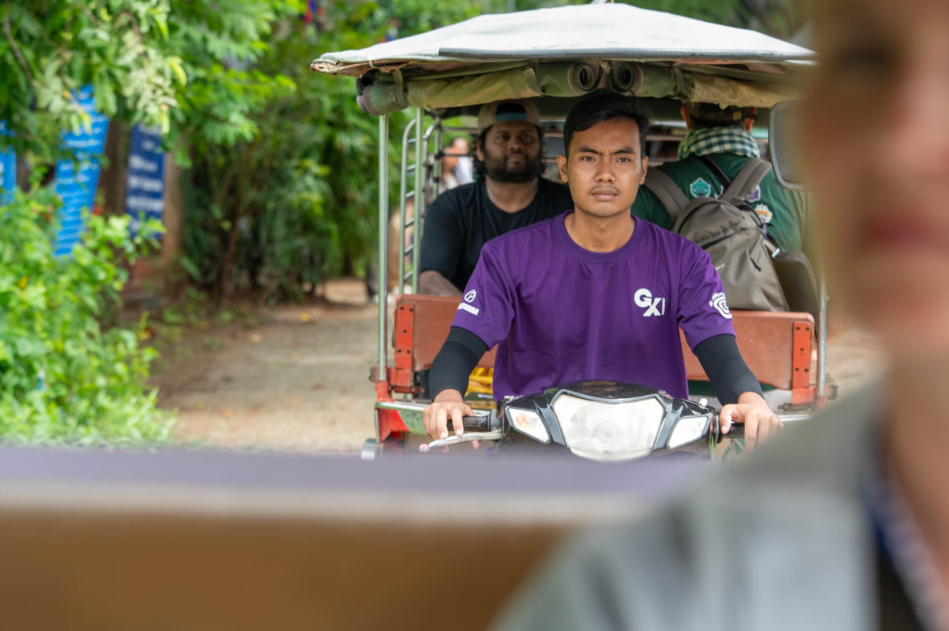 tuk-tuk driver transporting tourists in Southeast Asia on a motorized rickshaw