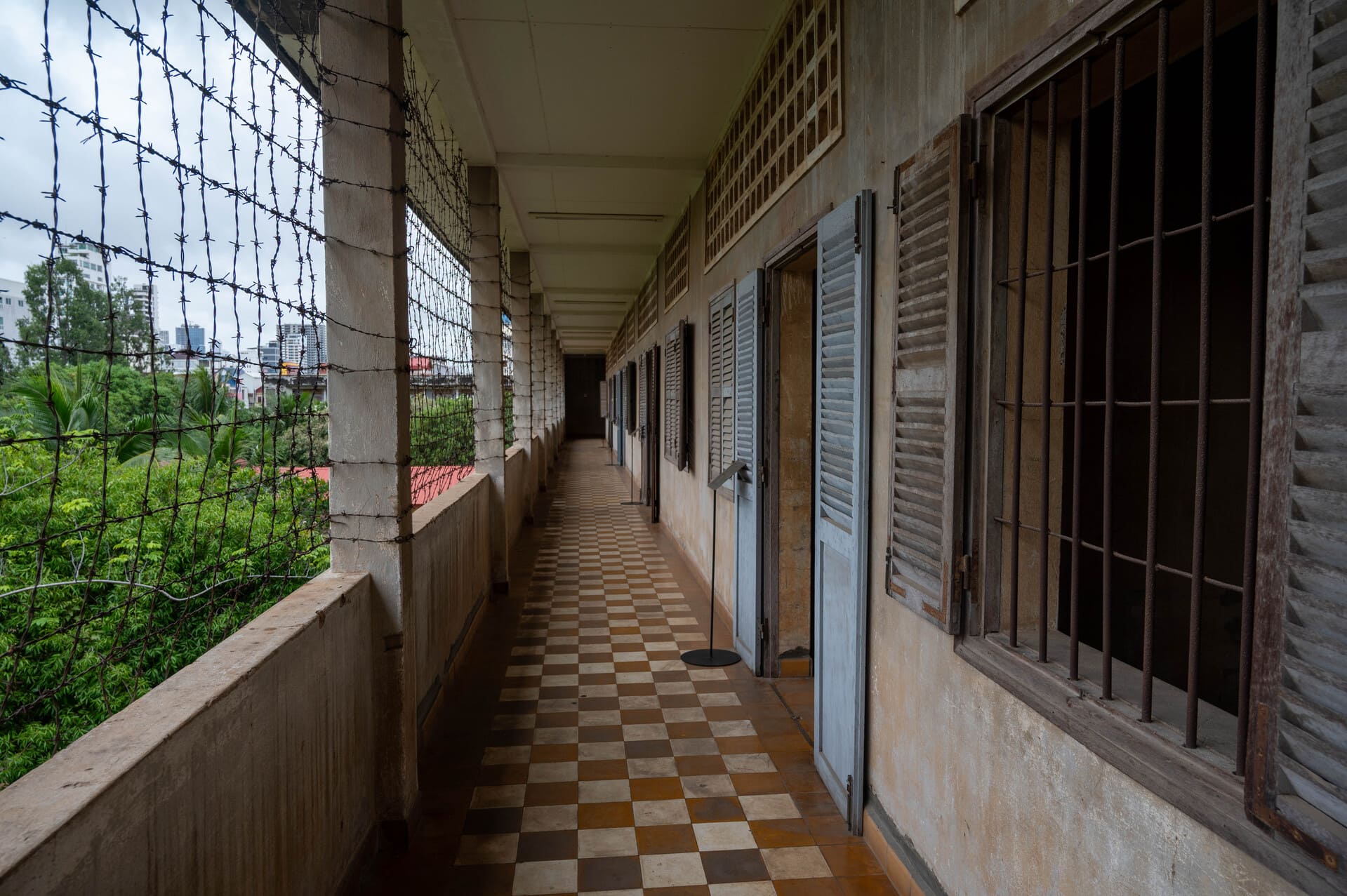 an outdoor corridor enclosed by security fencing and barbed wire at the Tuol Sleng Genocide Museum (S-21) in Phnom Penh, Cambodia